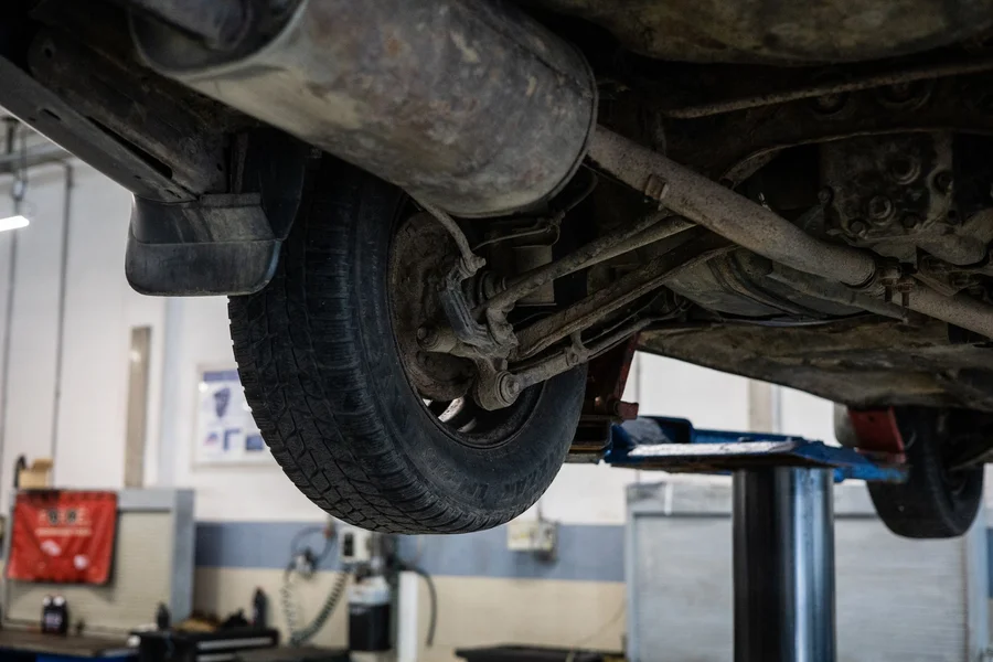 Mechanic working on car suspension undercarriage