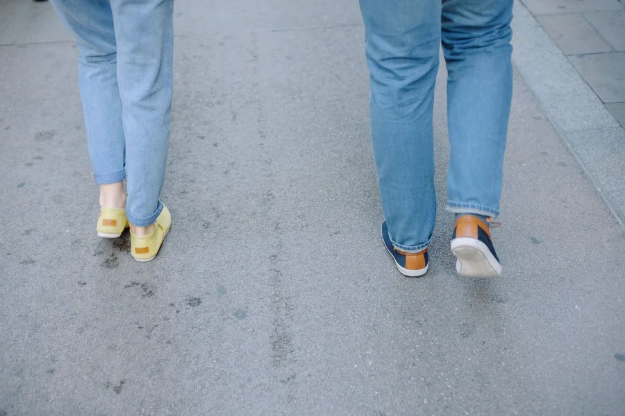 Brass Plum Sneakers Guide: Sizing, Comfort, and Styling Tips Person walking in casual low-top sneakers paired with denim jeans