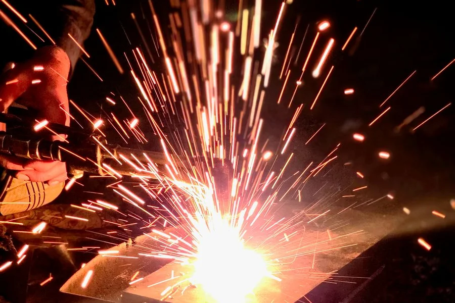 Metal worker shaping iron in a blacksmith workshop with sparks